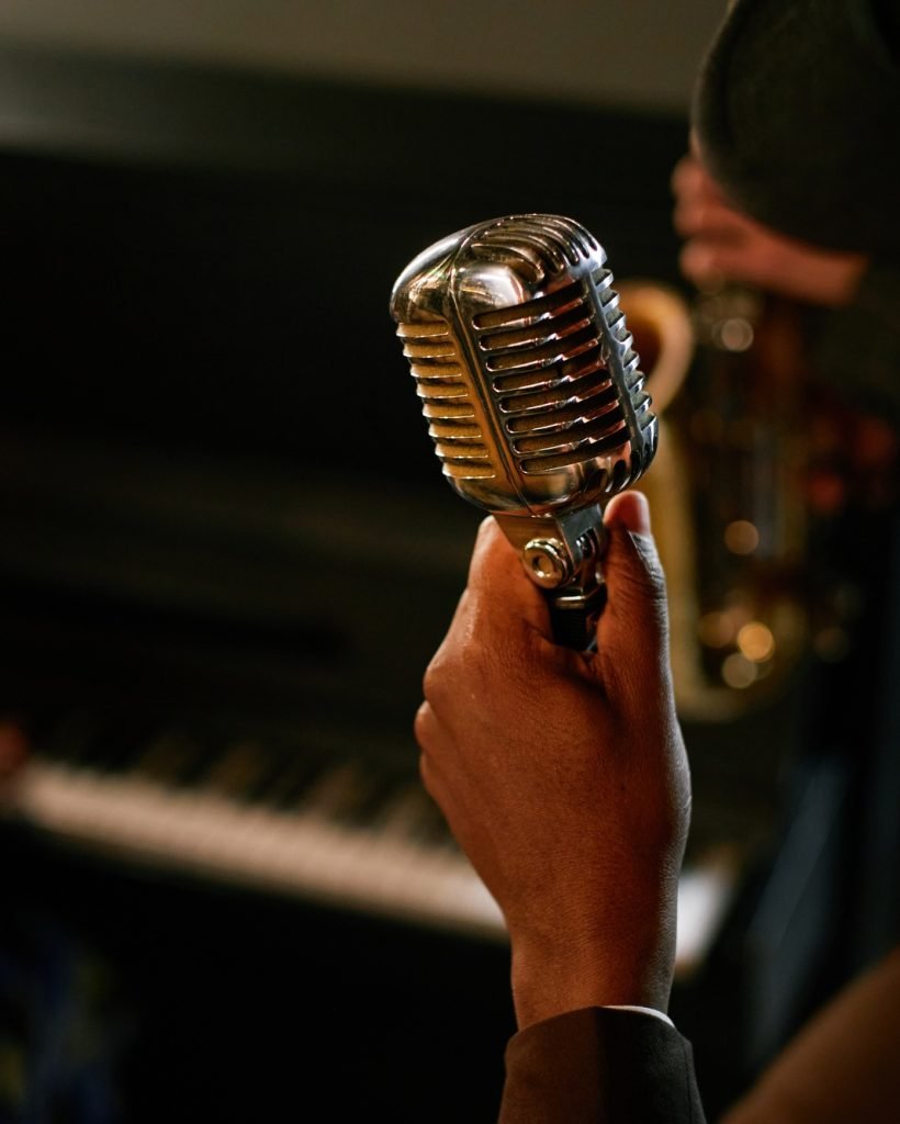 Male Singer Holding Retro Stage Mic while Performing Jazz with Band Indoors